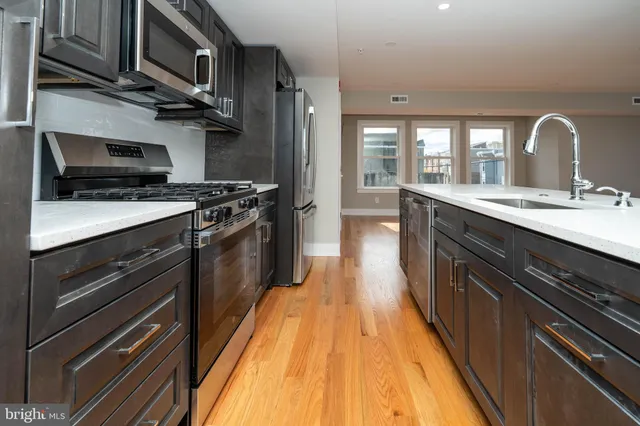 a kitchen with stainless steel appliances granite countertop a stove a sink and a microwave