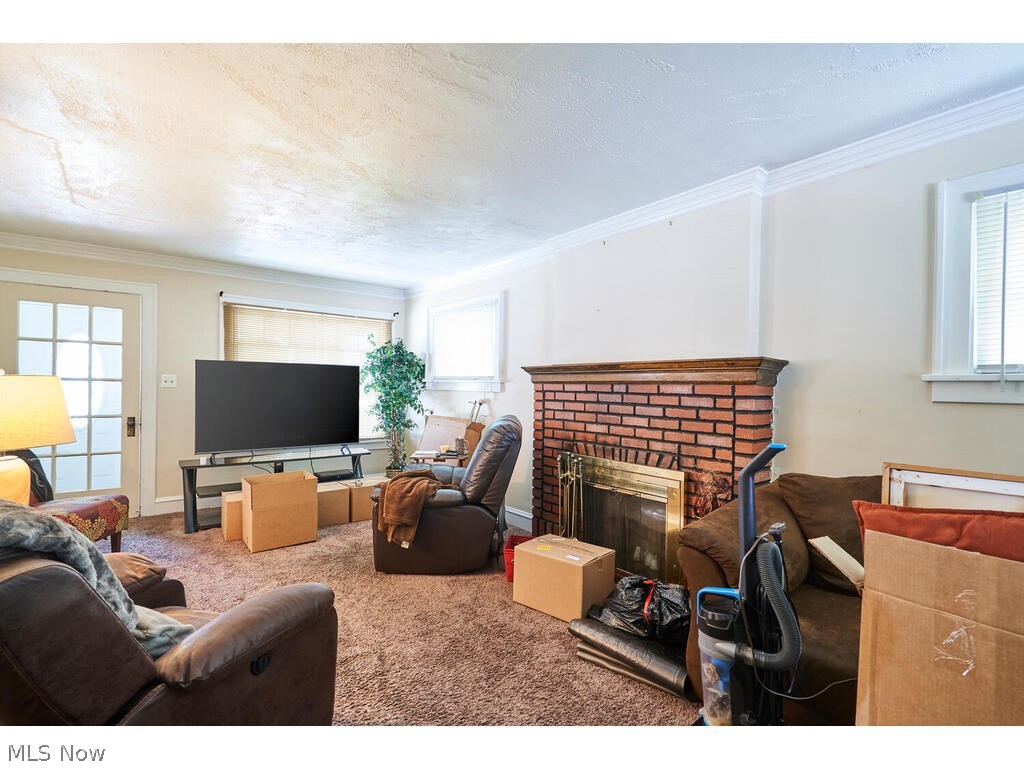 3975 Delmore Road Cleveland Heights, OH 44121 - Photo 7 of 27 Carpeted living room with a healthy amount of sunlight, a fireplace, and crown molding