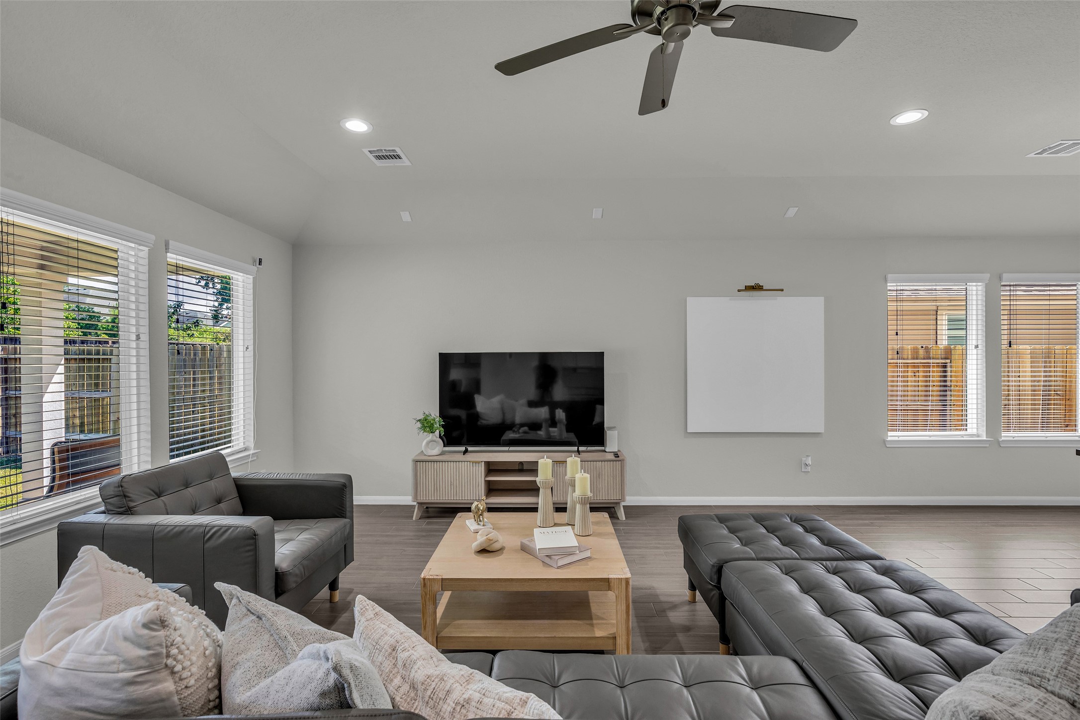 2344 Hagerman Road Conroe, TX 77384 - Photo 8 of 27 Living room with modern gray sofas, large windows offering natural light, and sleek wood flooring, perfect for relaxation and entertainment.