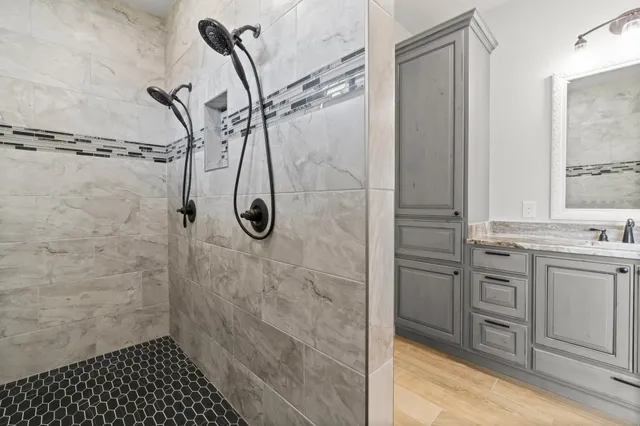 a bathroom with a granite countertop shower a sink and a mirror