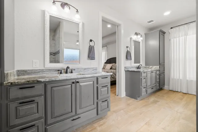 a bathroom with a granite countertop sink a toilet a mirror and shower