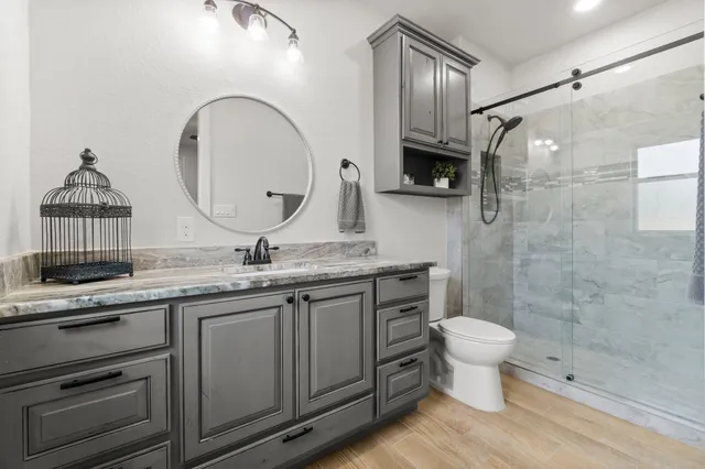 a bathroom with a granite countertop toilet a sink and a mirror
