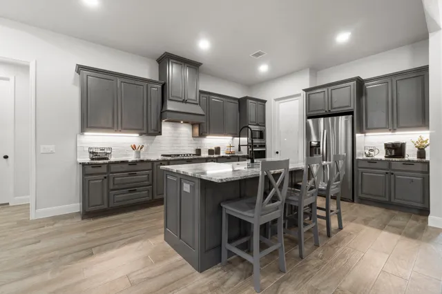 a kitchen with kitchen island granite countertop wooden cabinets and stainless steel appliances