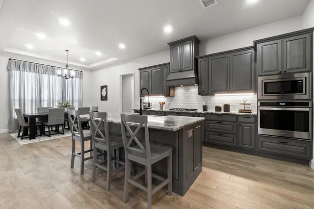 a kitchen with kitchen island granite countertop wooden cabinets and stainless steel appliances