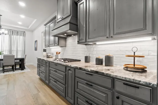 a kitchen with granite countertop a sink a stove and cabinets