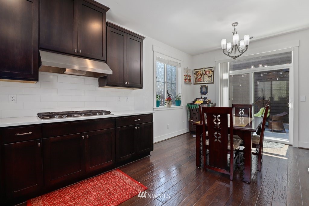 4606 187th Place Southeast Bothell, WA 98012 - Photo 13 of 40 a kitchen with granite countertop stainless steel appliances a dining table chairs cabinets and stove top oven