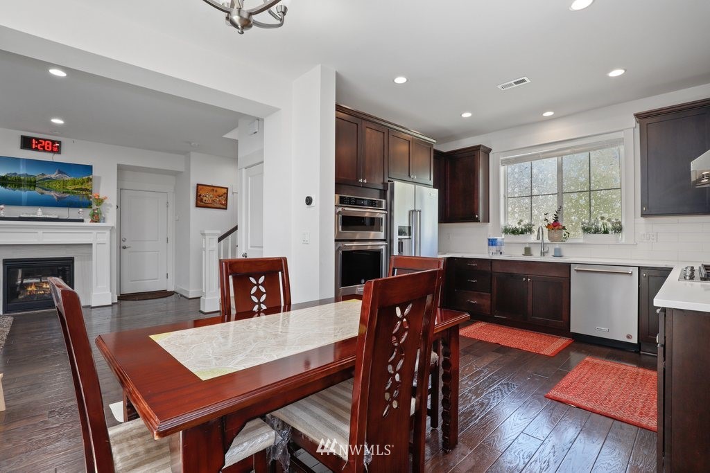 4606 187th Place Southeast Bothell, WA 98012 - Photo 8 of 40 a kitchen with stainless steel appliances granite countertop a stove a refrigerator a sink dishwasher a dining table and chairs with wooden floor
