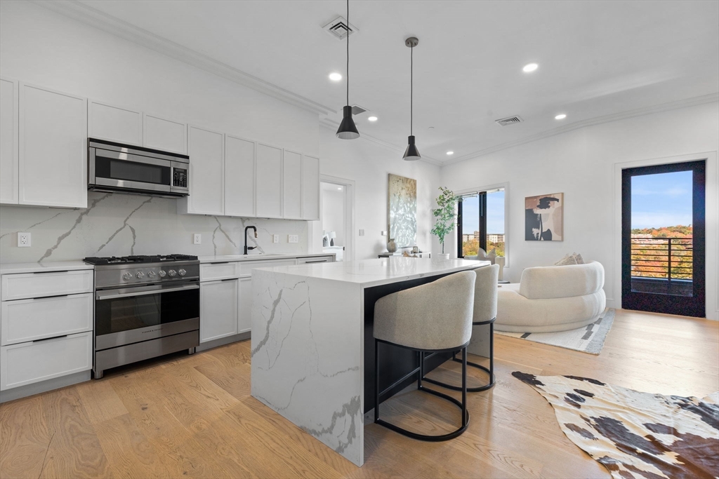 a kitchen with stainless steel appliances granite countertop a stove a sink dishwasher a dining table and chairs with wooden floor