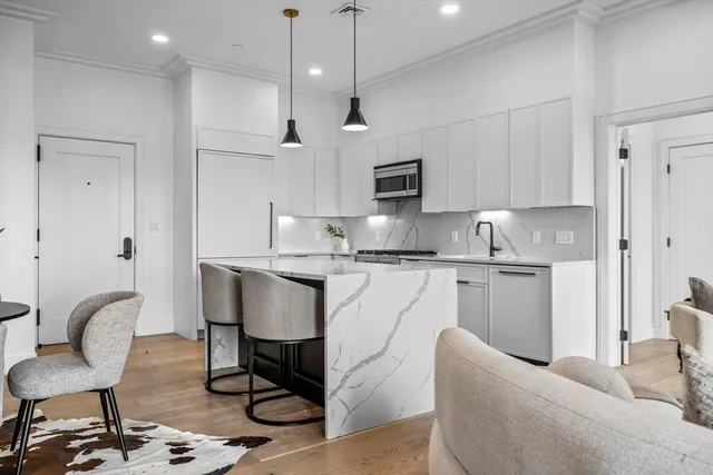 a kitchen with kitchen island a dining table chairs refrigerator and microwave