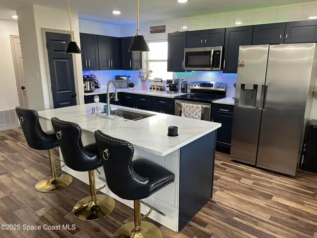 a kitchen with stainless steel appliances kitchen island granite countertop a refrigerator a stove a sink a dining table and chairs