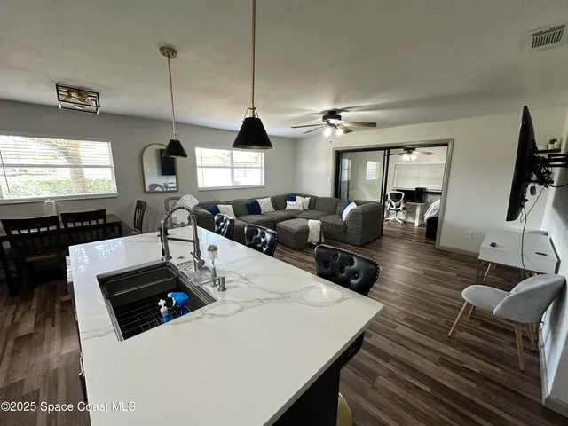 a kitchen with stainless steel appliances kitchen island granite countertop a stove a sink a dining table and chairs with wooden floor