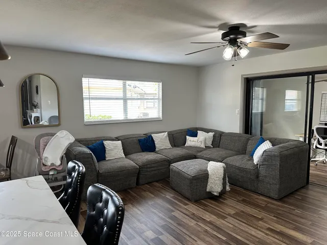 a living room with furniture and a large mirror next to a window