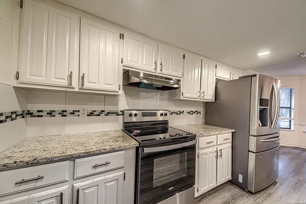 a kitchen with granite countertop a stove sink and refrigerator