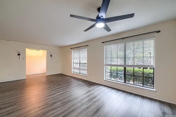 a view of an empty room with wooden floor and a window