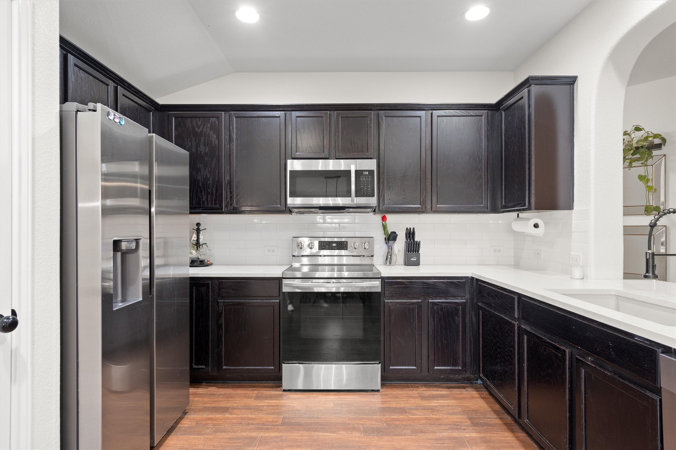 606 Old Peak Road Georgetown, TX 78626 - Photo 5 of 23 Kitchen with dark wood cabinetry, stainless steel appliances, white subway tile backsplash, white countertops, and wood-finish flooring