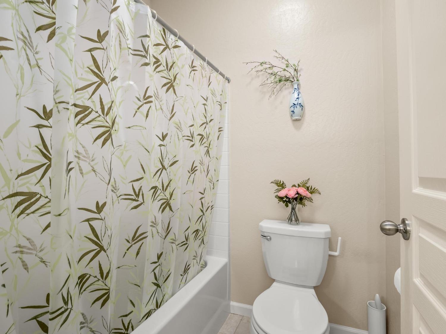 1012 Las Rosas Avenue Clovis, CA 93619 - Photo 15 of 36 a bathroom with a toilet and a shower curtain