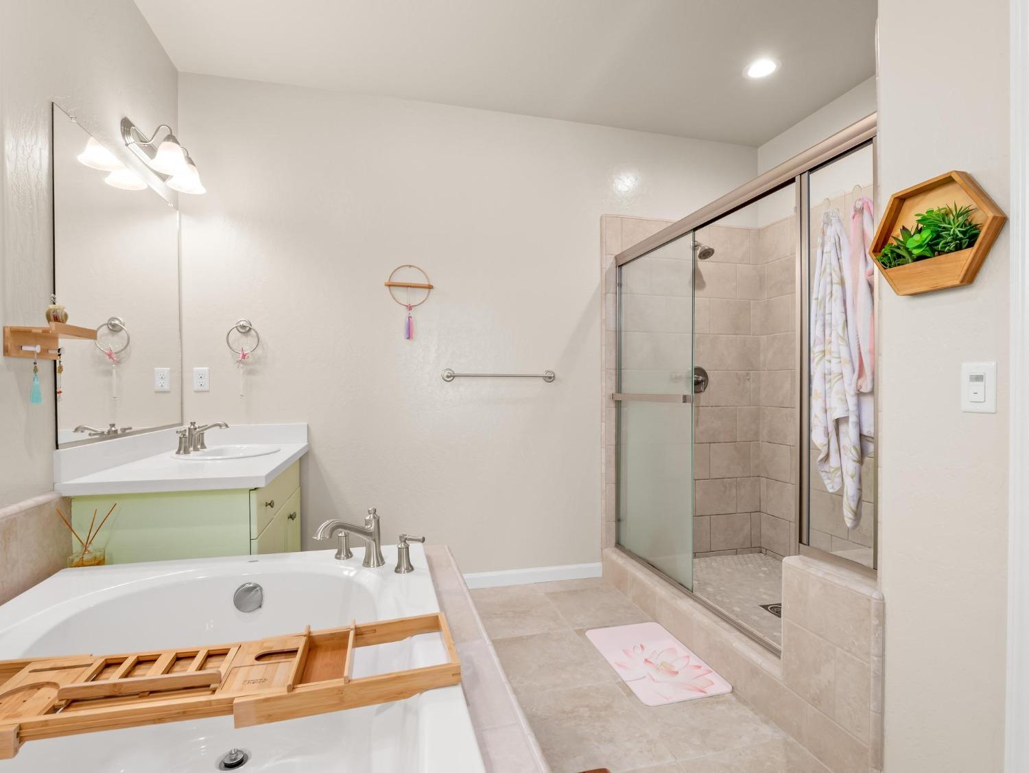 1012 Las Rosas Avenue Clovis, CA 93619 - Photo 25 of 36 a bathroom with a tub a mirror and a shower