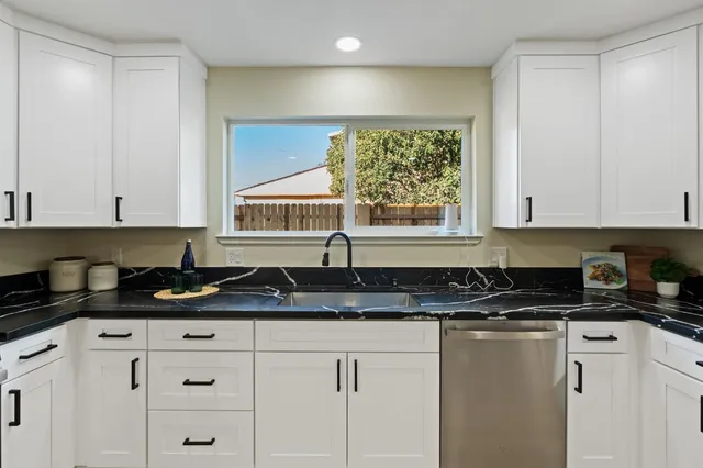 a kitchen with granite countertop white cabinets and a stove