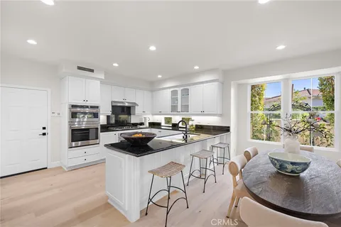 a kitchen with stainless steel appliances kitchen island granite countertop a stove a sink a microwave a dining table and chairs