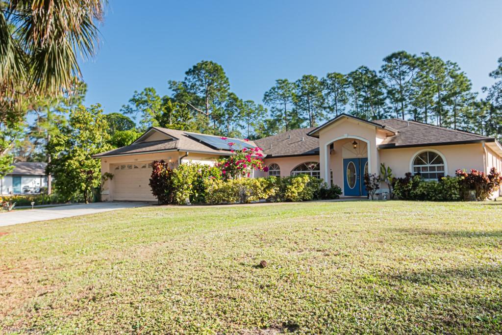 590 6th Street Northeast Naples, FL 34120 - Photo 2 of 50 Single story home with stucco siding, a front yard, concrete driveway, and an attached garage