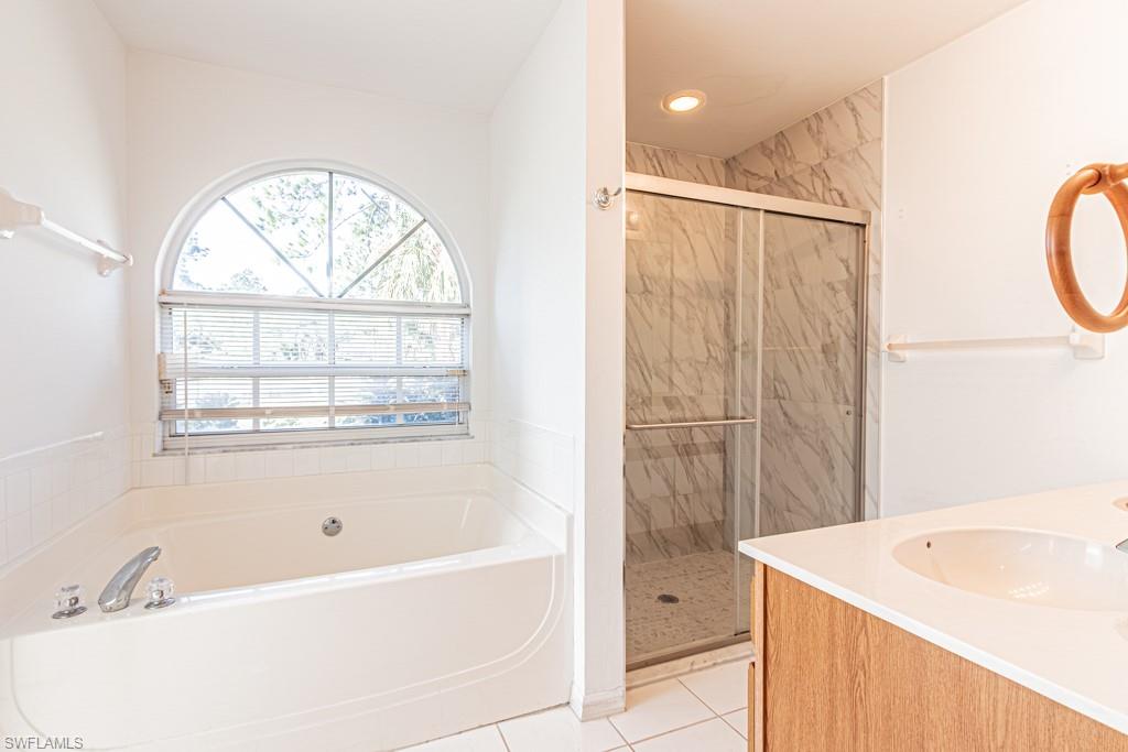 590 6th Street Northeast Naples, FL 34120 - Photo 31 of 50 Bathroom with vanity, a walk-in shower, spa-style bathtub, and light tile patterned floors