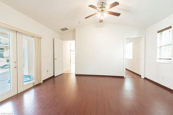 an empty room with wooden floor fan and windows
