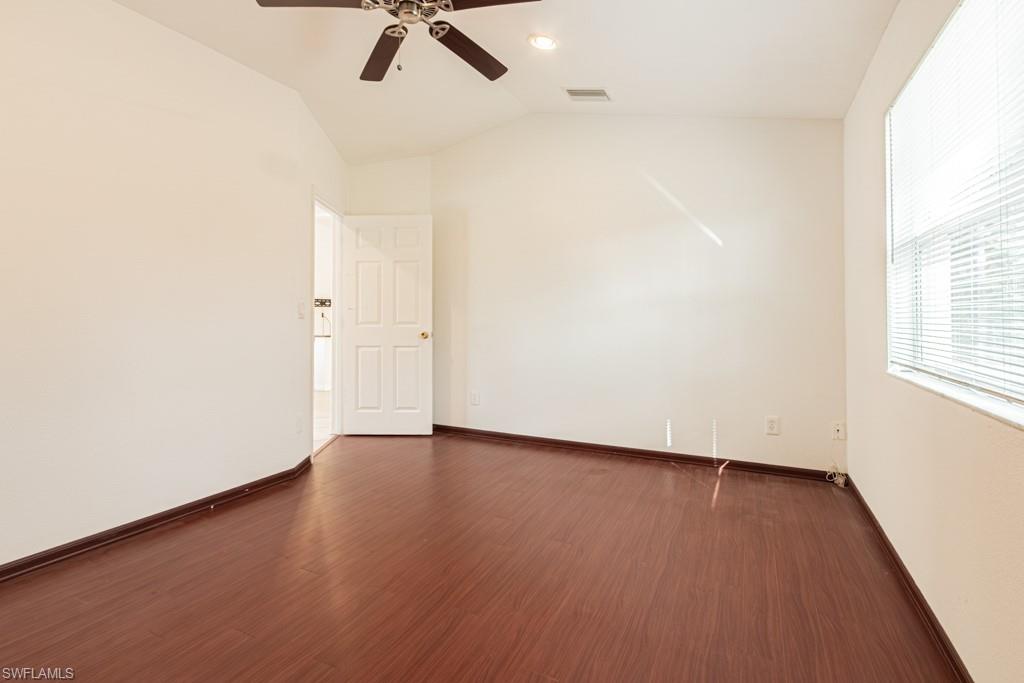 590 6th Street Northeast Naples, FL 34120 - Photo 38 of 50 Bedroom with french doors, plenty of natural light, dark wood-style floors, and vaulted ceiling