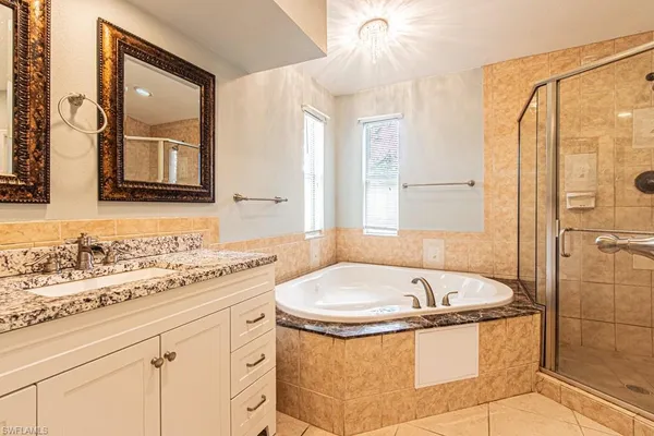 a bathroom with a granite countertop sink and a bathtub