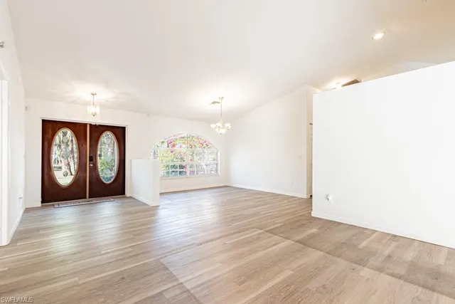 an empty room with large window and wooden floor