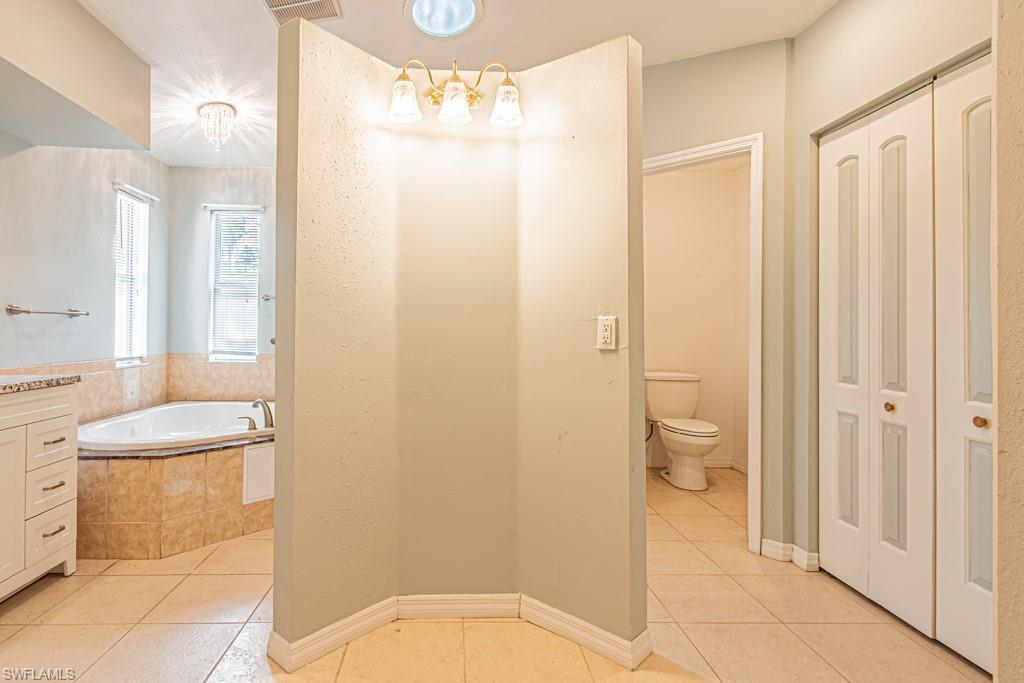 590 6th Street Northeast Naples, FL 34120 - Photo 42 of 50 Bathroom featuring a bath, light tile patterned floors, a closet, and vanity