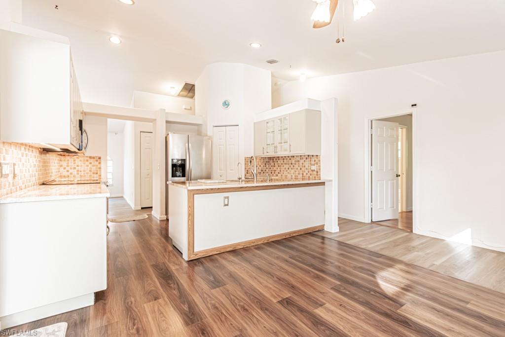590 6th Street Northeast Naples, FL 34120 - Photo 9 of 50 Kitchen featuring a peninsula, stainless steel fridge, dark wood-style floors, and white cabinetry