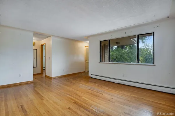 a view of an empty room with wooden floor and a window