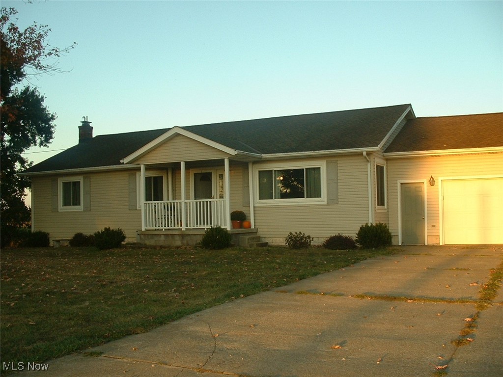 Ranch-style house with a garage, concrete driveway and mature trees