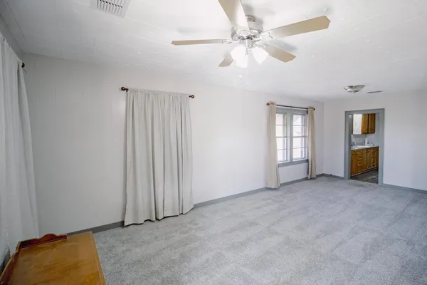 an empty room with windows and fan