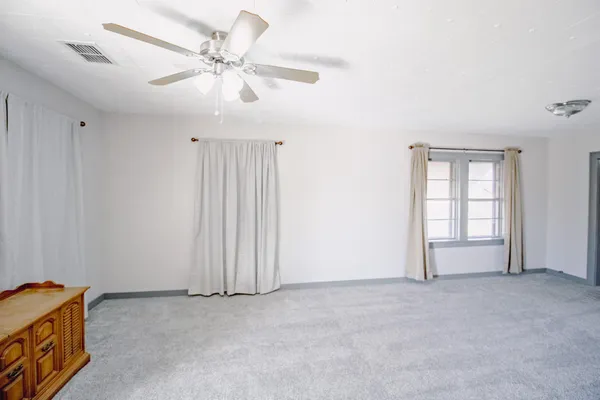 an empty room with windows and fan