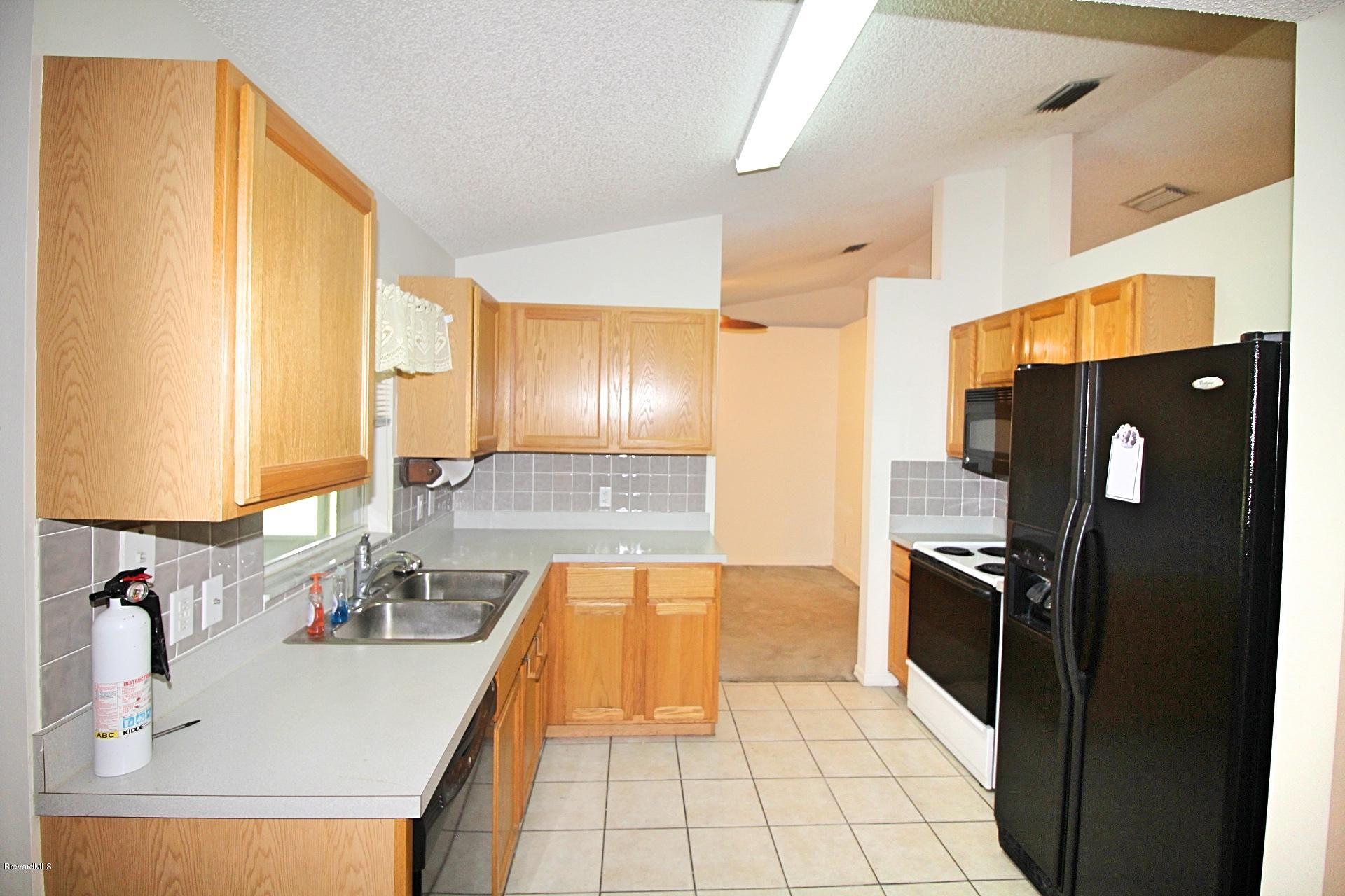 724 Riviera Drive Northeast Palm Bay, FL 32905 - Photo 3 of 13 a kitchen with stainless steel appliances a refrigerator sink and stove