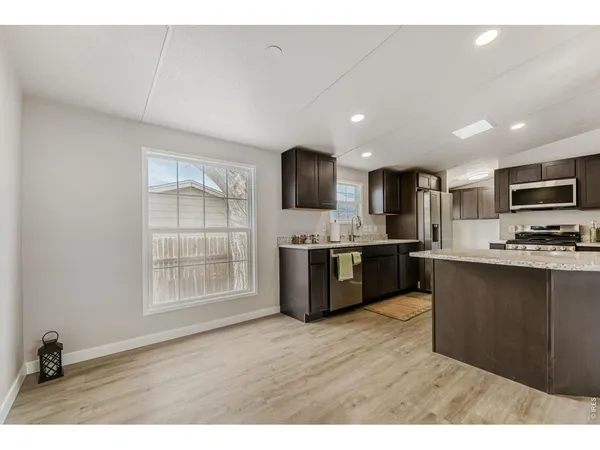 a kitchen with stainless steel appliances kitchen island granite countertop a refrigerator a sink a stove a microwave and wooden cabinets