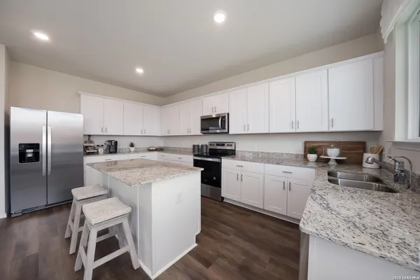 a kitchen with granite countertop white cabinets and stainless steel appliances