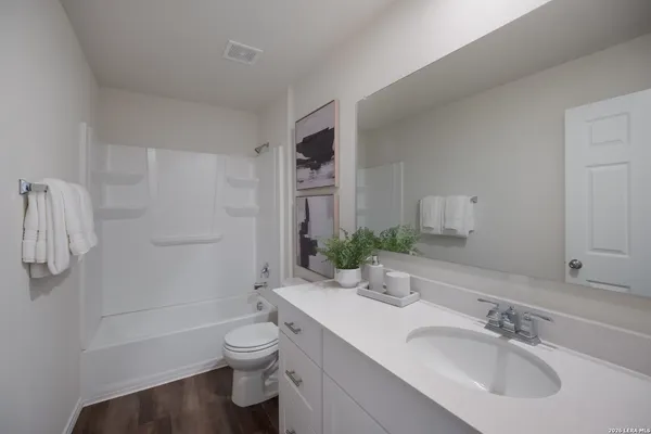 a bathroom with a toilet a sink a tub and mirror