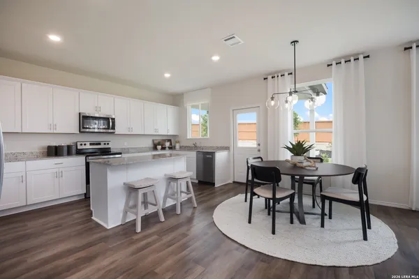 a kitchen with a table chairs a sink dishwasher stove and cabinets with wooden floor