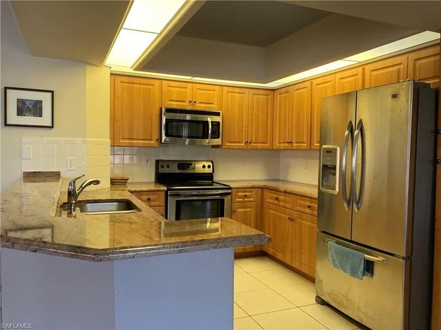 a kitchen with stainless steel appliances granite countertop a refrigerator a stove top oven a sink dishwasher and microwave