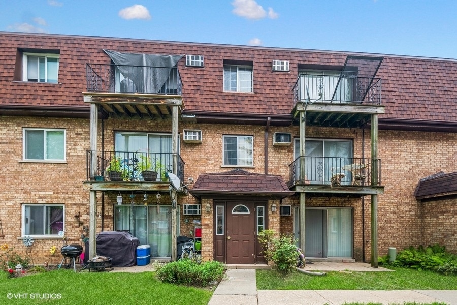 115 East Dundee Road, Unit 1S Wheeling, IL 60090 - Photo 1 of 9 a front view of a house with garden