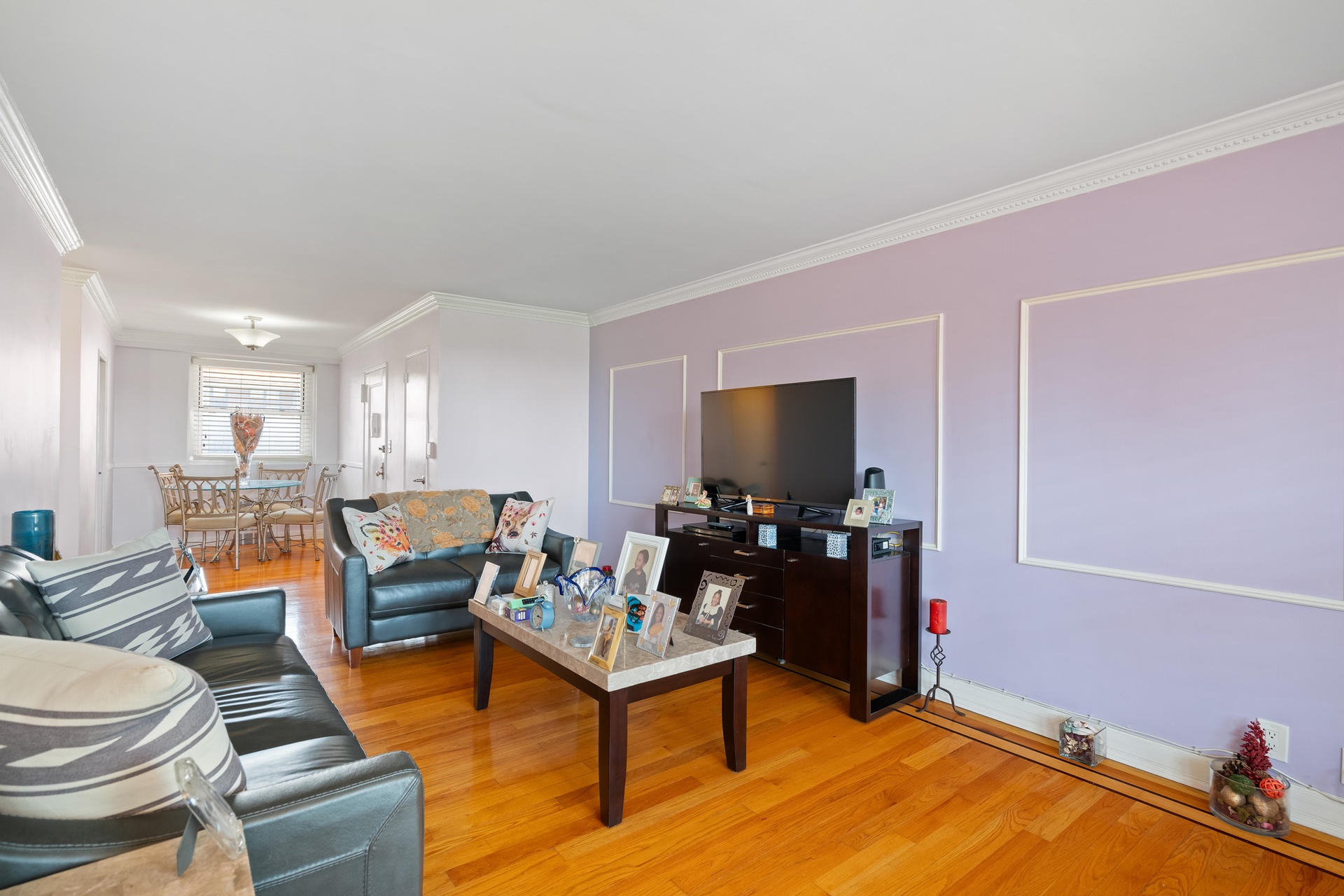 35-31 85th Street, Unit 8L Queens, NY 11372 - Photo 2 of 14 a living room with furniture a flat screen tv and kitchen view