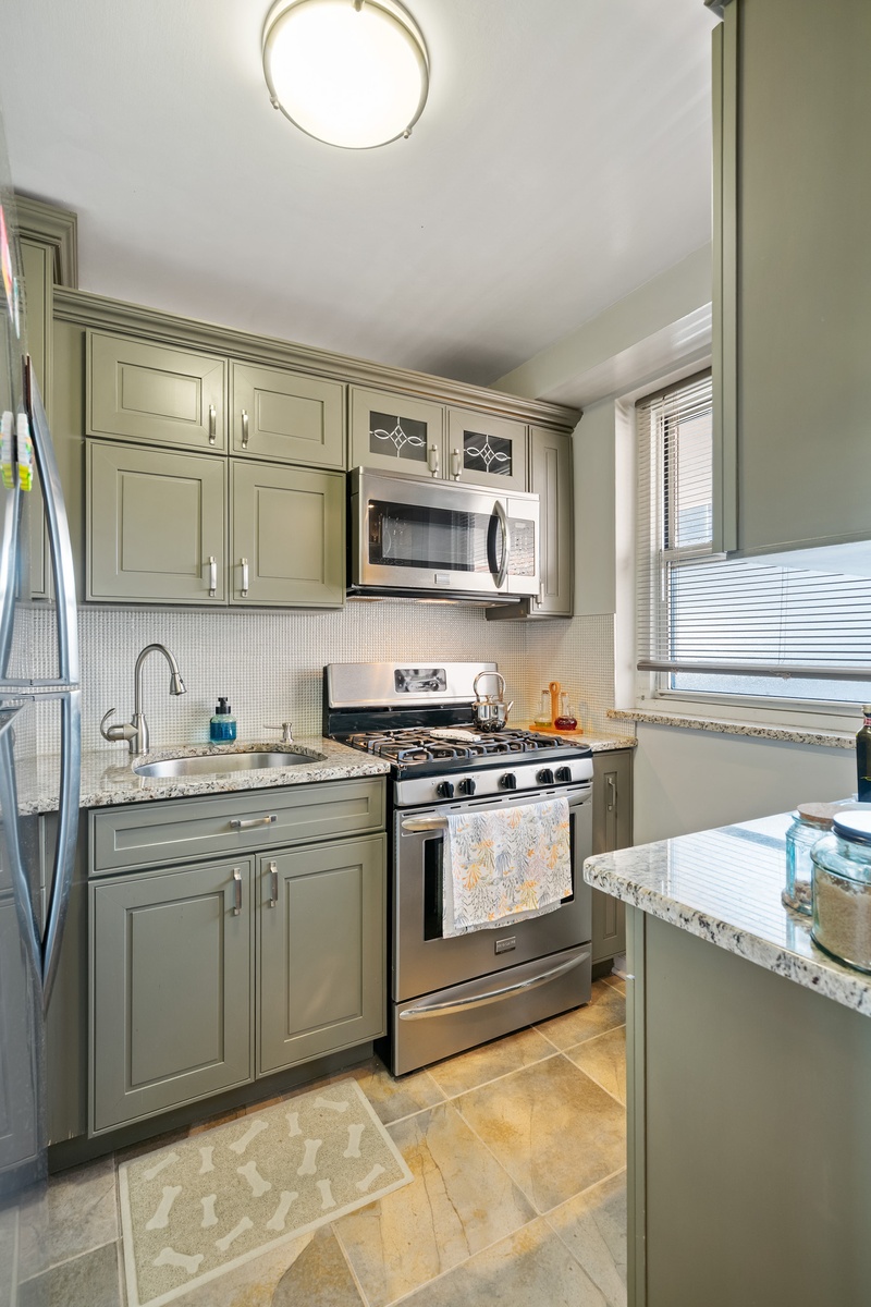 35-31 85th Street, Unit 8L Queens, NY 11372 - Photo 5 of 14 a kitchen with stainless steel appliances granite countertop a sink and stove top oven