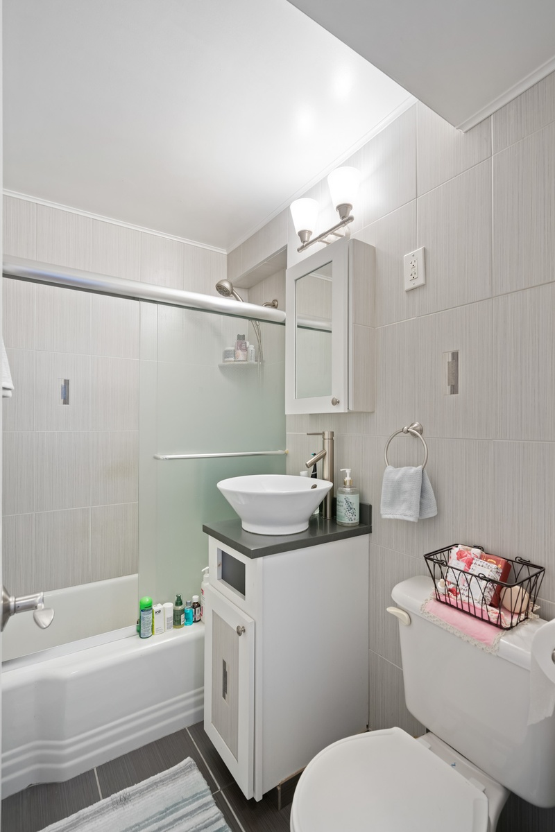 35-31 85th Street, Unit 8L Queens, NY 11372 - Photo 8 of 14 a bathroom with a sink a toilet and shower