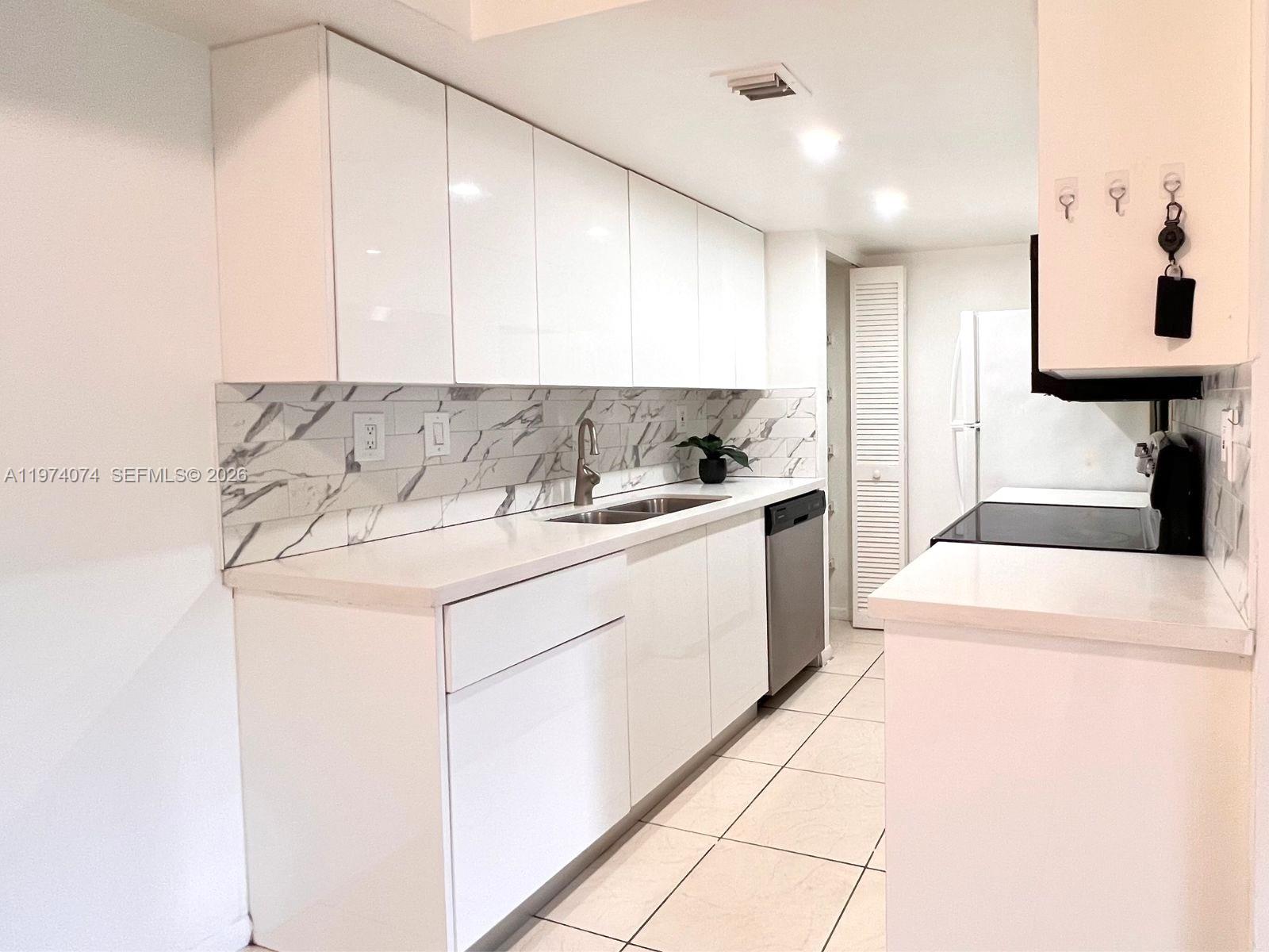 8911 Southwest 123rd Court, Unit 101 Miami, FL 33186 - Photo 4 of 15 a kitchen that has a sink and a stove in it