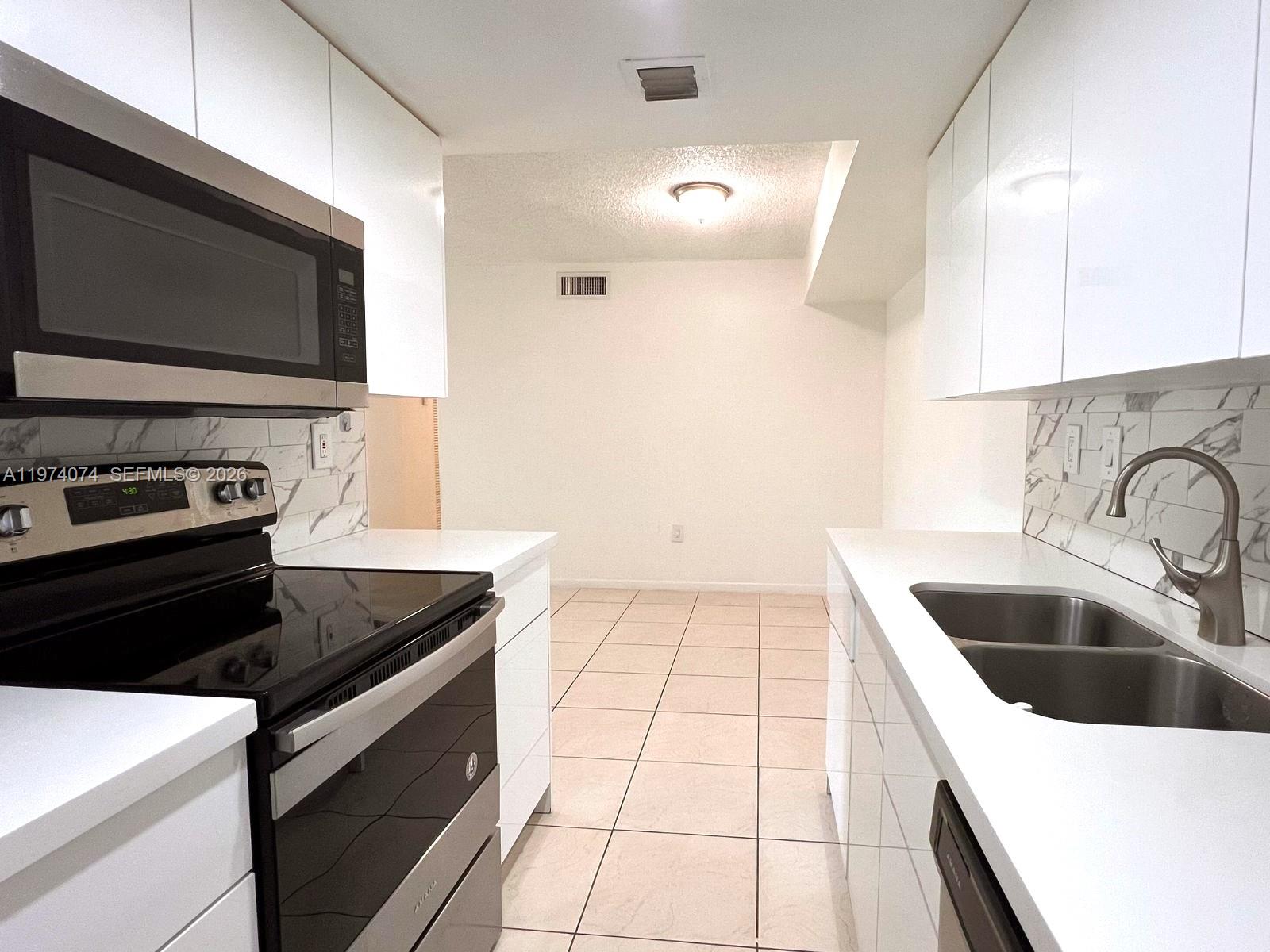 8911 Southwest 123rd Court, Unit 101 Miami, FL 33186 - Photo 6 of 15 a kitchen with a sink and a stove top oven