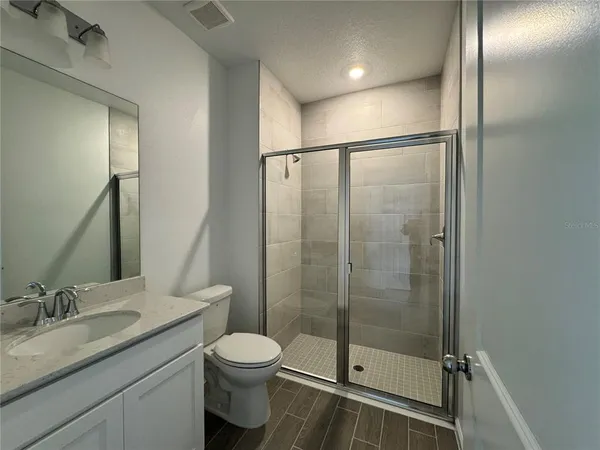 a bathroom with a shower sink vanity mirror and toilet