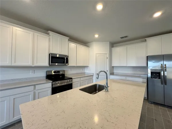 a kitchen with stainless steel appliances granite countertop a sink a stove a refrigerator a microwave and cabinets