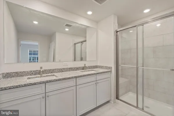 a bathroom with a granite countertop sink a mirror and a shower
